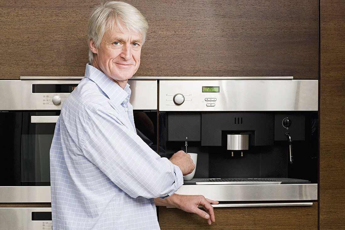 Mann mittleren Alters wartet auf Kaffee aus Kaffeemaschine