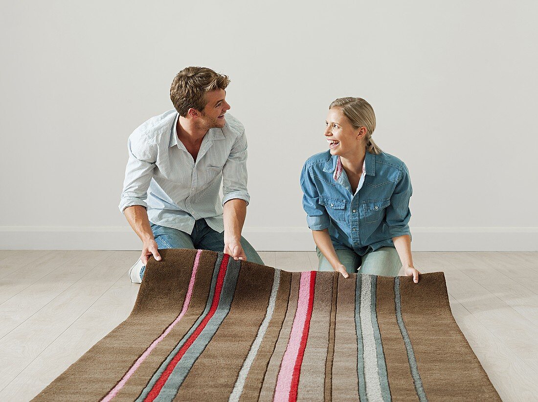 A young couple unrolling a rug