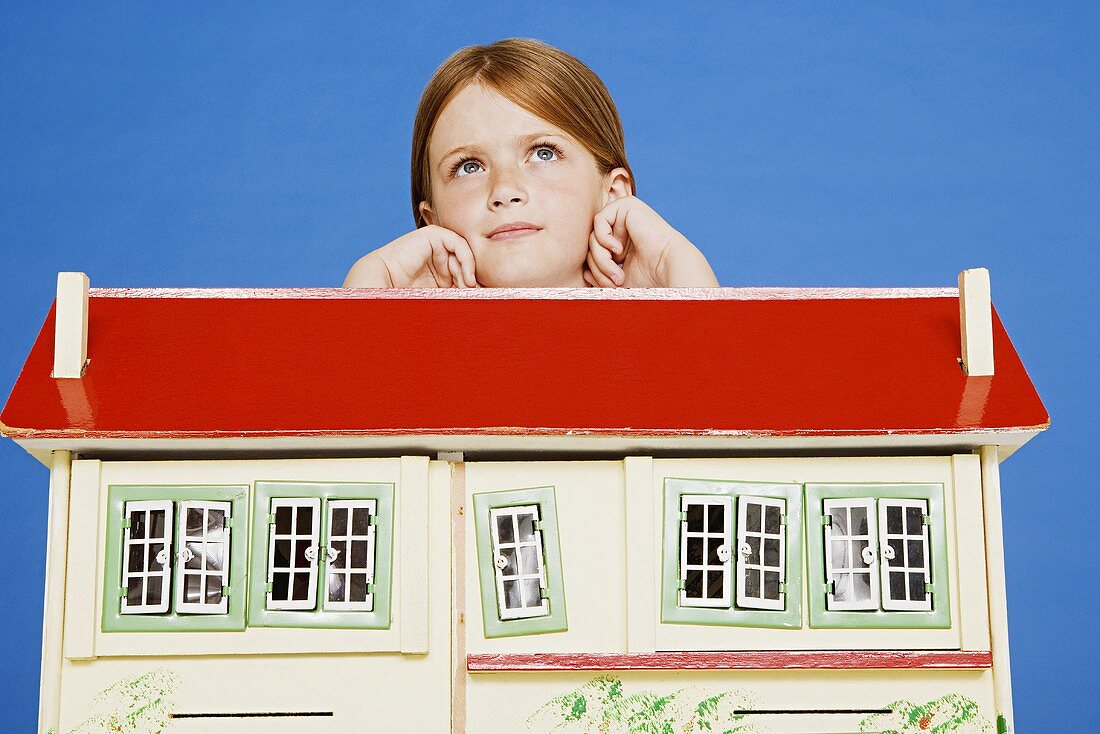 A girl leaning on a dolls' house