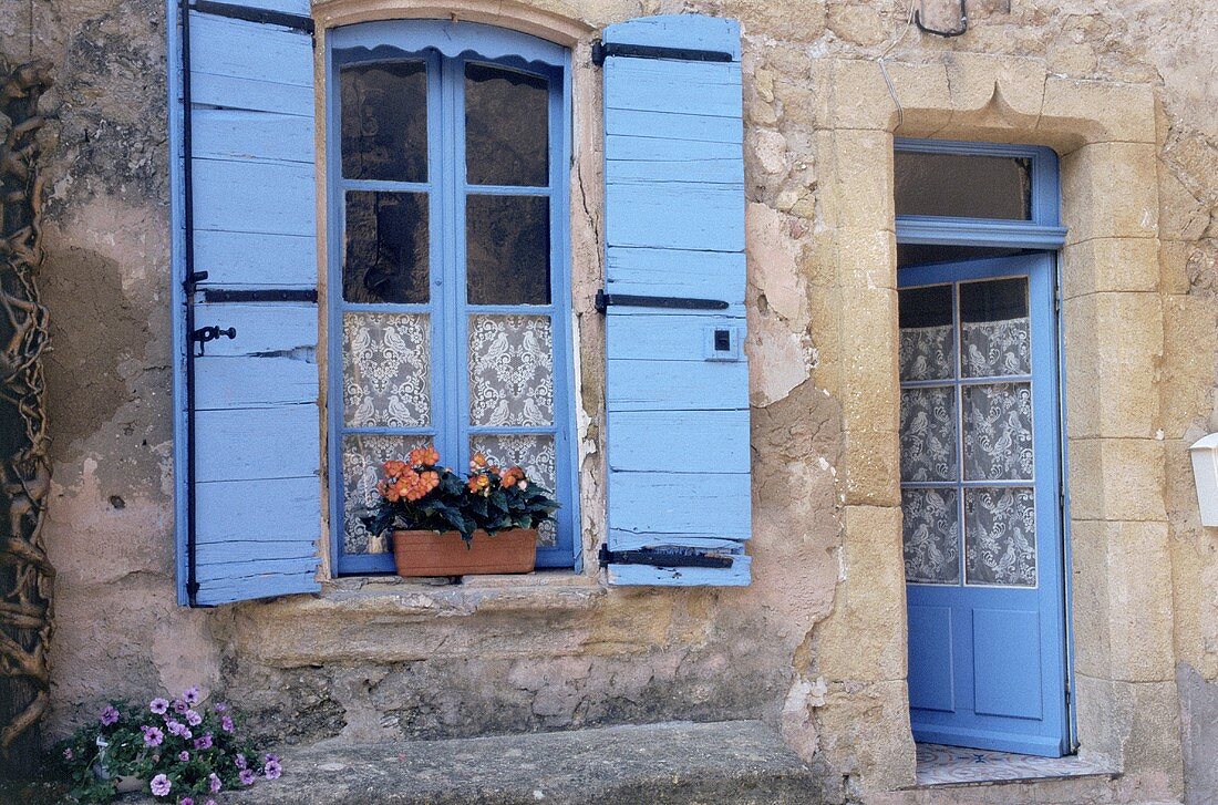 Altes Haus mit geöffneten, pastellblauen Fensterläden und pastellblauer Haustür (Lauris, Luberon, Frankreich)