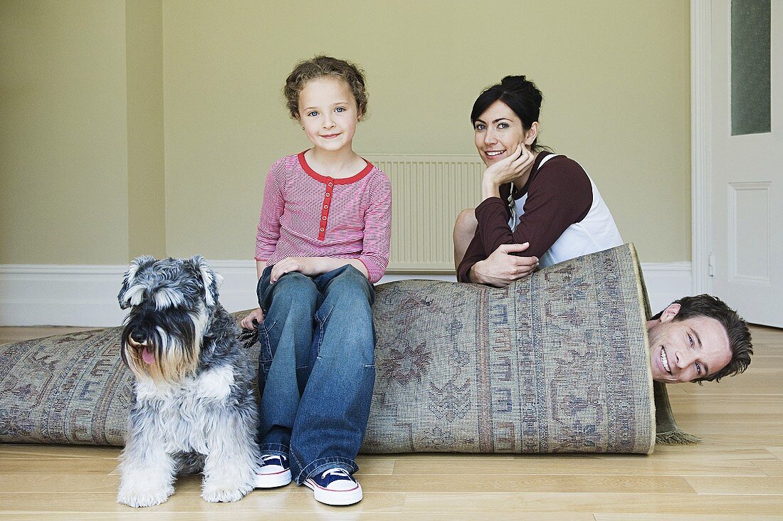 Vater, in einen Teppich eingerollt, Frau, Tochter und Hund