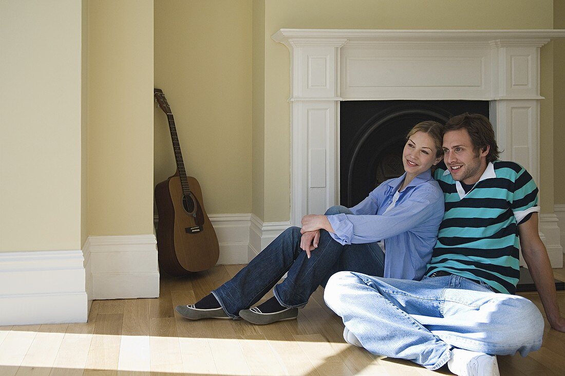 A young couple sitting on the floor in front of a fireplace