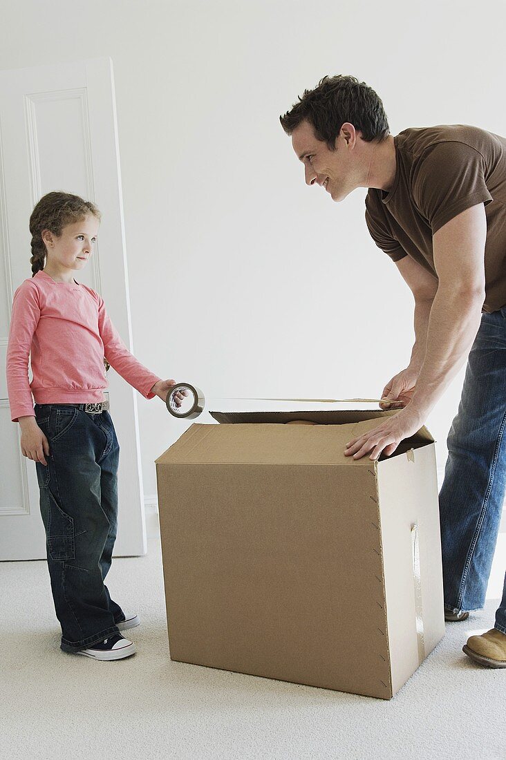 A father and daughter taping a box closed