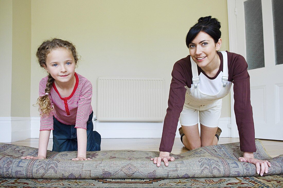 Mutter und Tochter rollen den Teppich auf