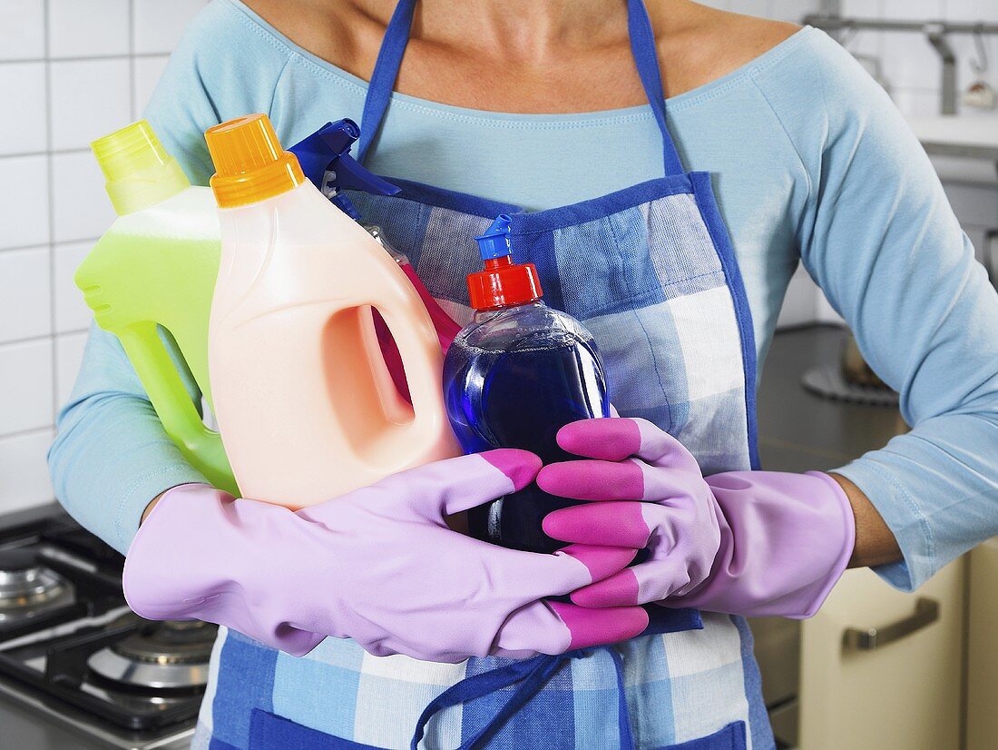 A woman holding various cleaning products