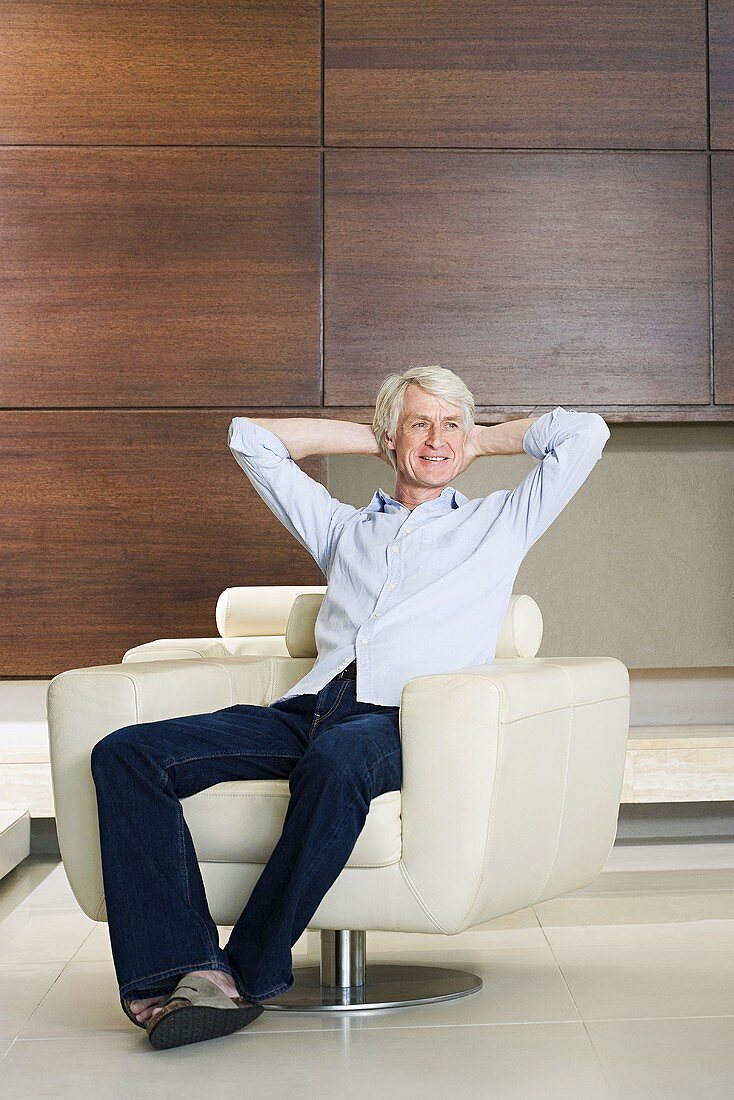 A middle aged man relaxing in a modern armchair