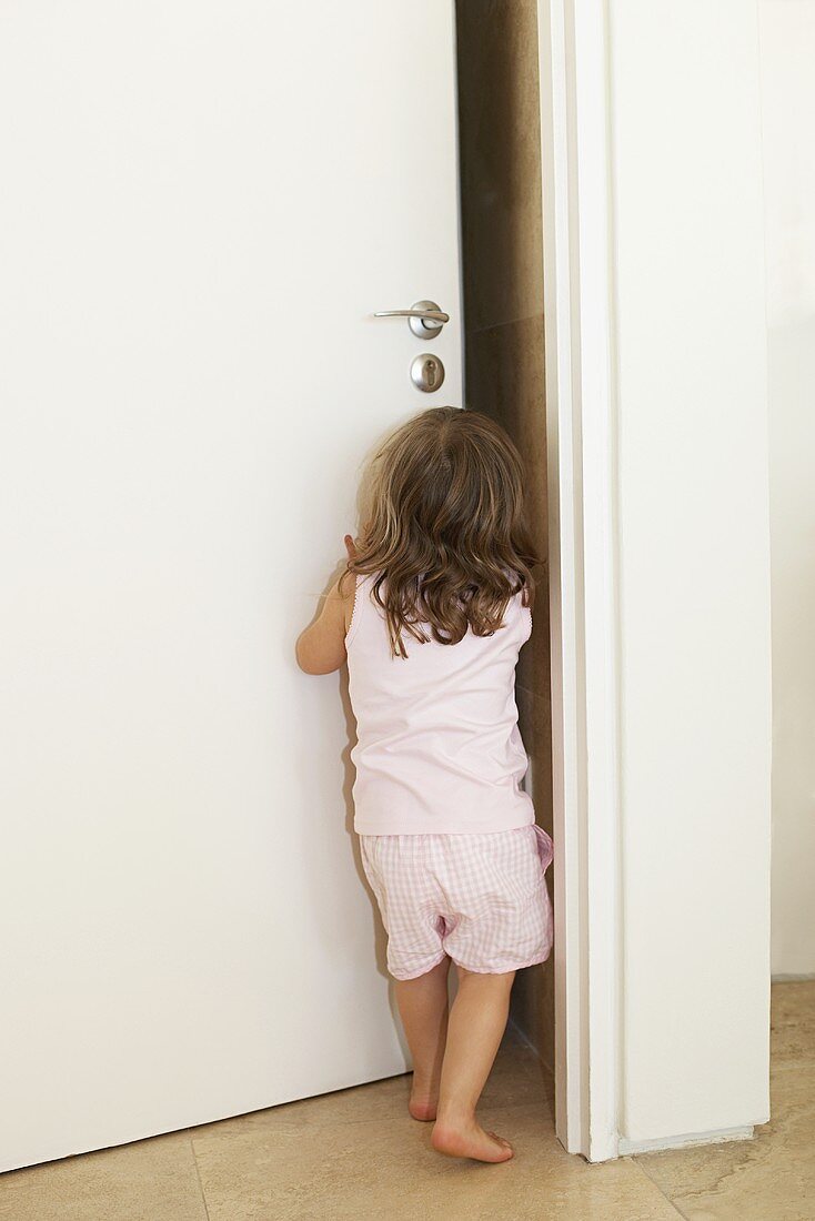 A young girl pushing open a door