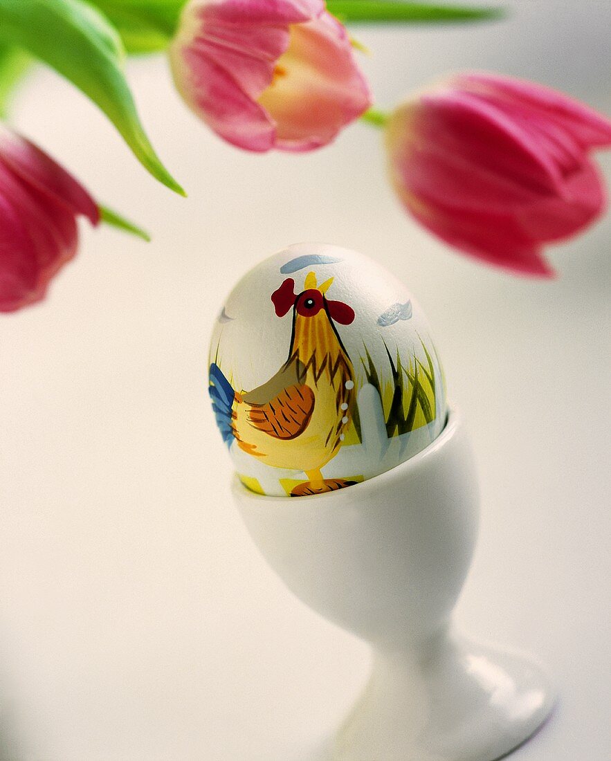 A painted Easter egg with tulips in the background