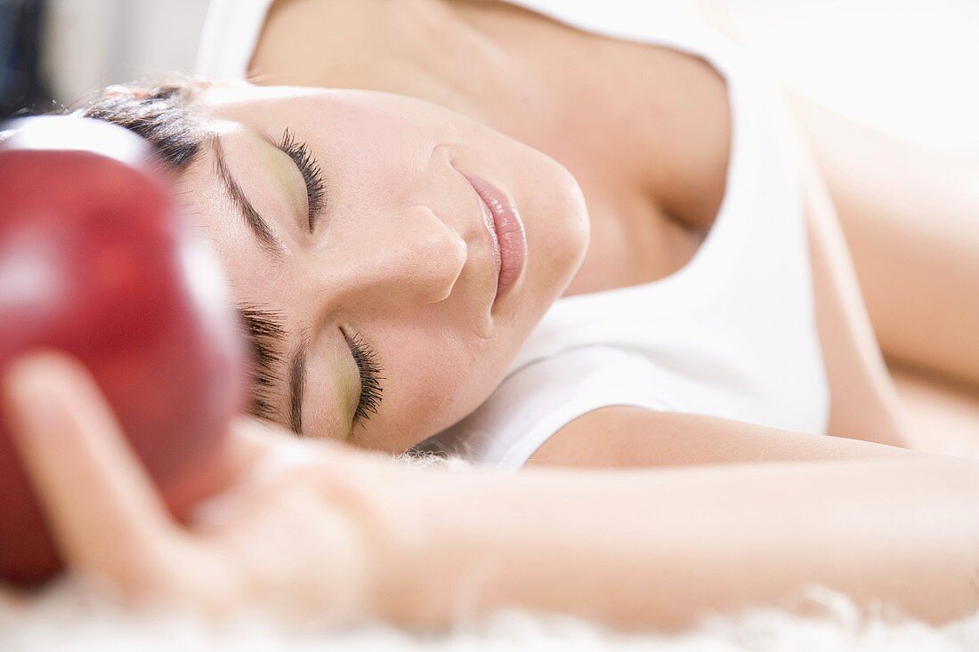 Young woman lying down holding an apple