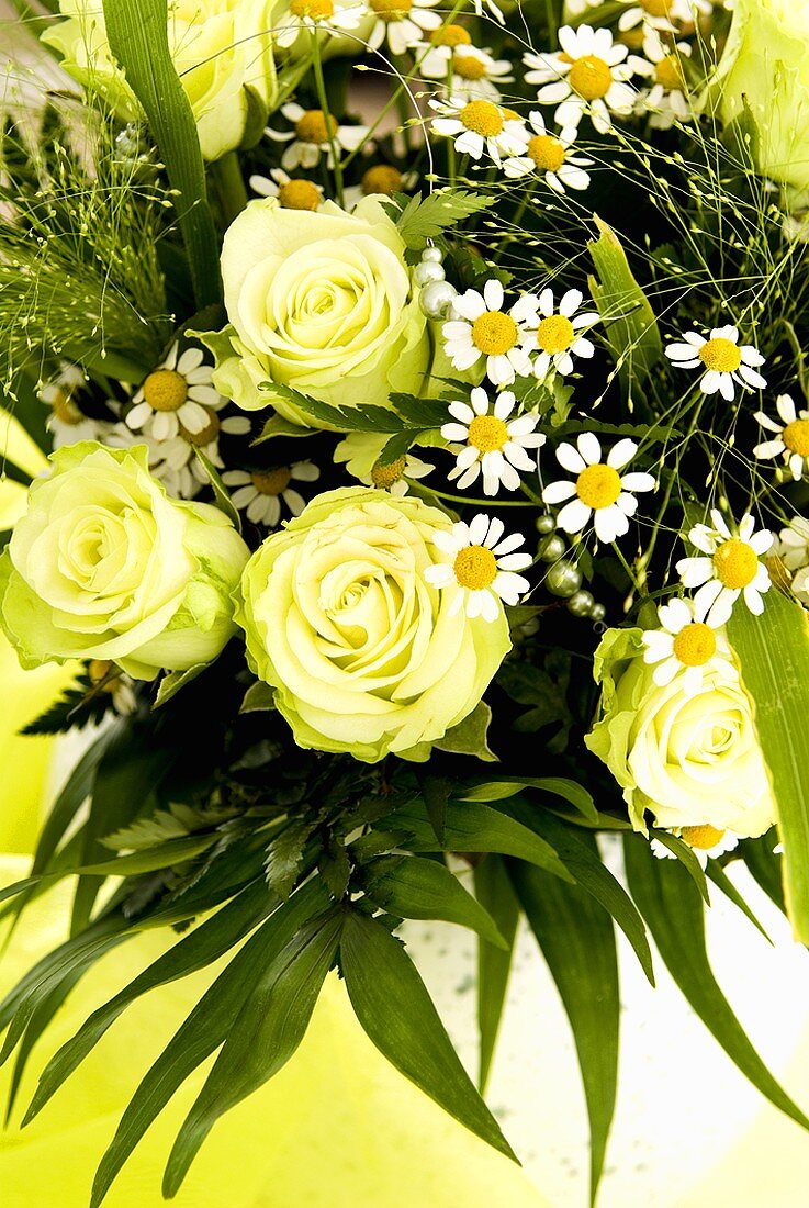 Arrangement of white roses, chamomile flowers and grasses