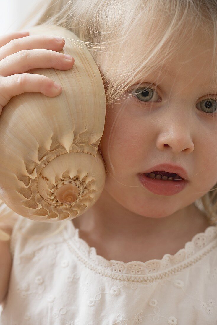 Girl listening to a shell in wonderment
