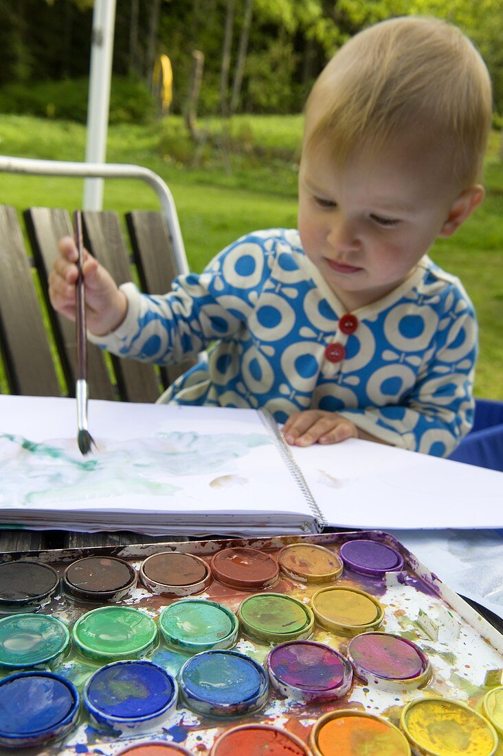 Kleines Mädchen malt mit Wasserfarben