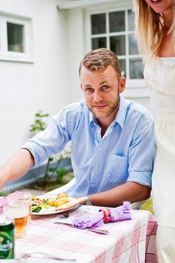 Junger Mann & junge Frau beim Essen im Garten