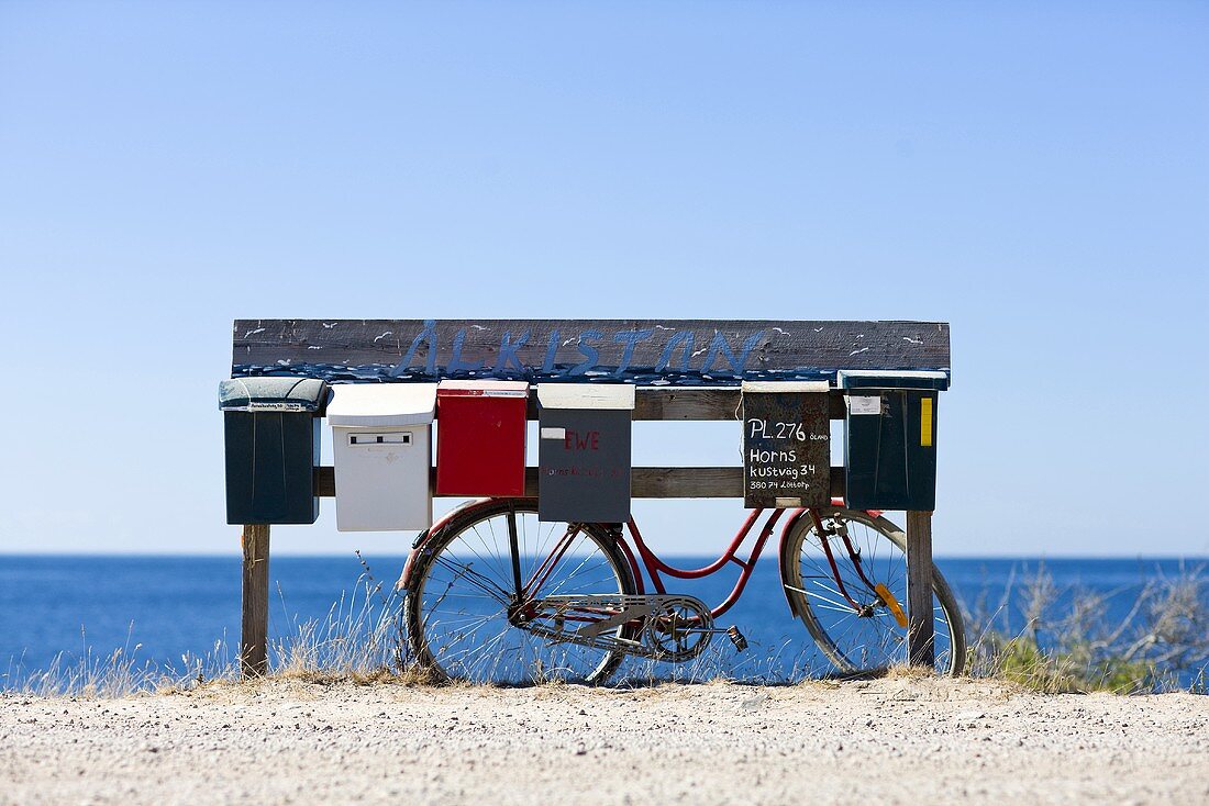 A bike leaning against mailboxes, the ocean in the background