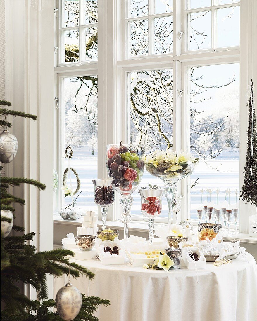 Festlich dekorierter Tisch zum Weihnachtsfest vor Fenster mit Blick auf schneebedeckte Landschaft