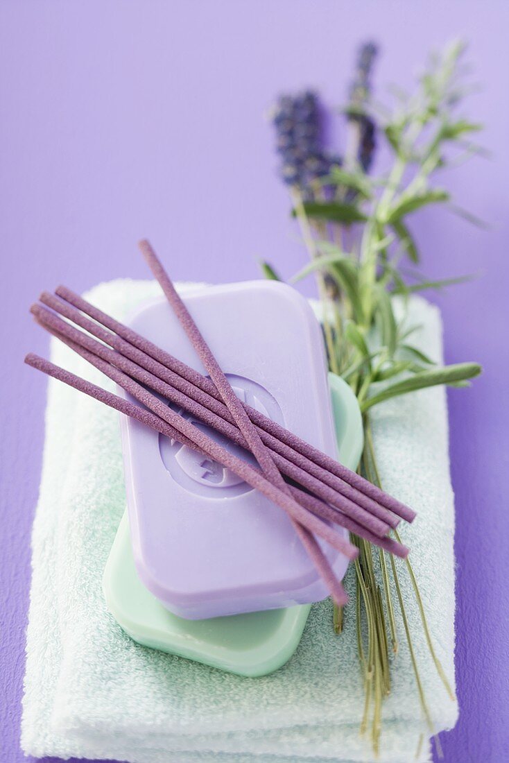 Incense sticks & bars of soap on towel, sprig of lavender
