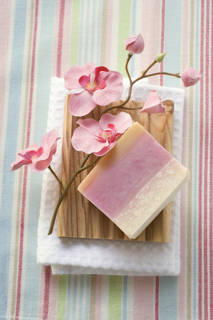 Soap and flowers on wooden soap dish on towel
