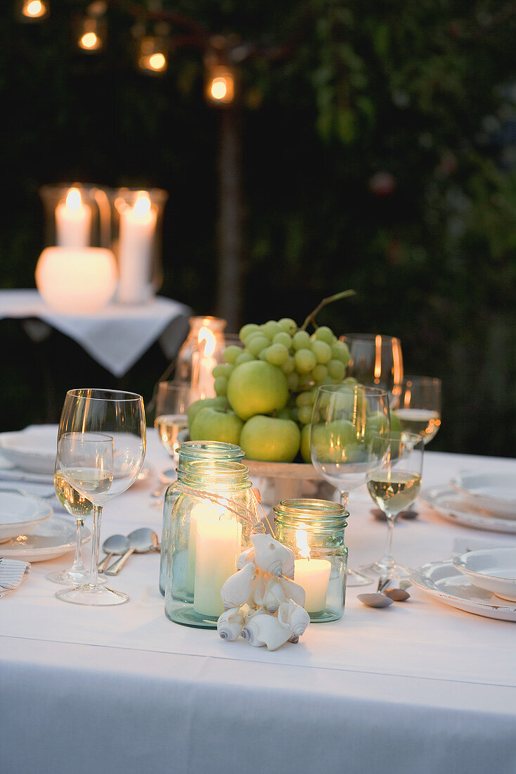 Gedeckter Tisch im Garten mit Obstschale und Windlichtern