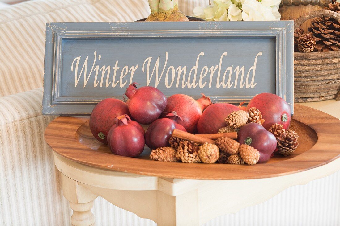 Weihnachtsdeko mit Granatäpfeln, Zapfen und Schild