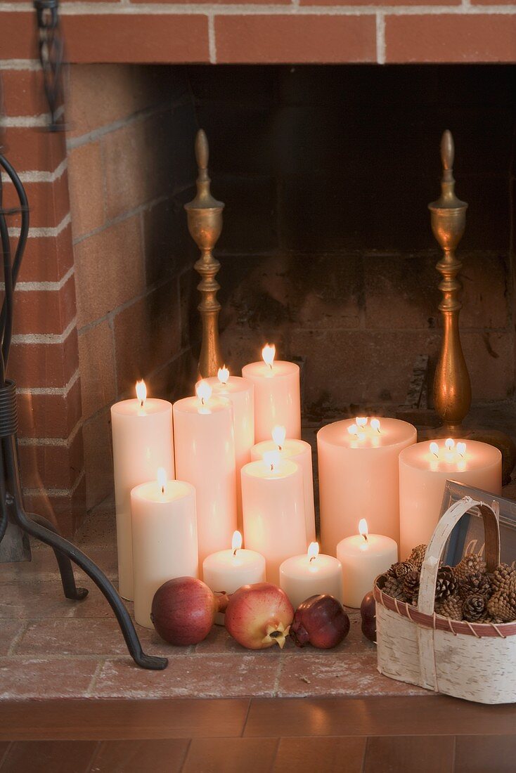 Kerzen, Granatäpfel und Zapfen vor Kamin