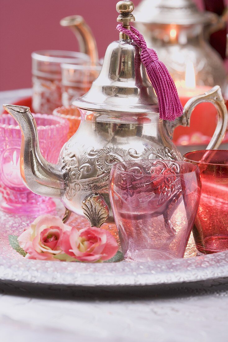 Silberne Teekanne, Gläser, Rosen und Windlichter auf Tablett