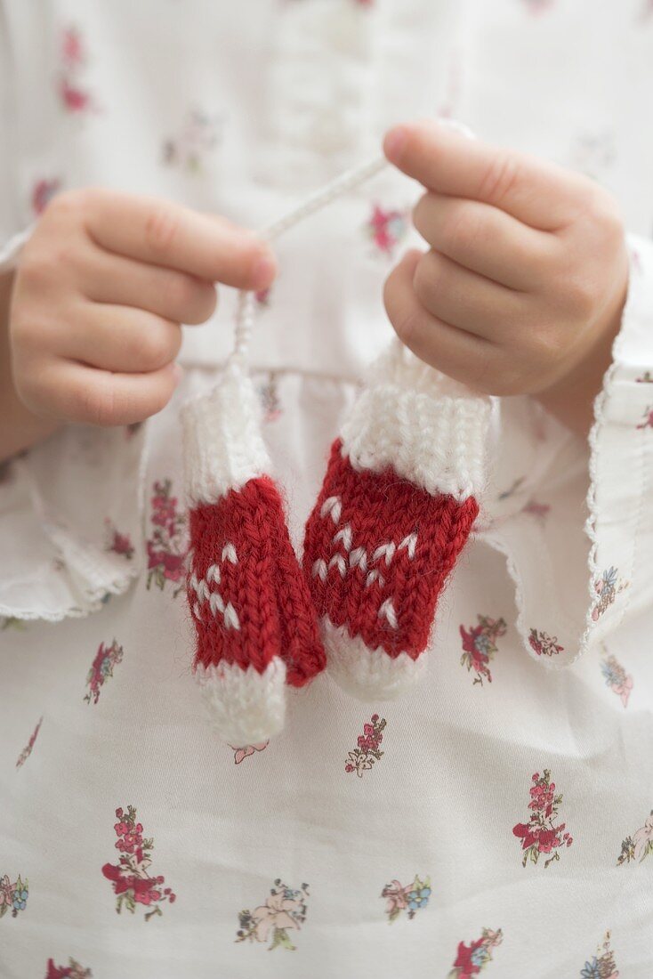 Small girl holding knitted mittens