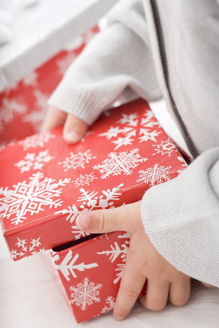 Small girl opening box with snowflake motifs