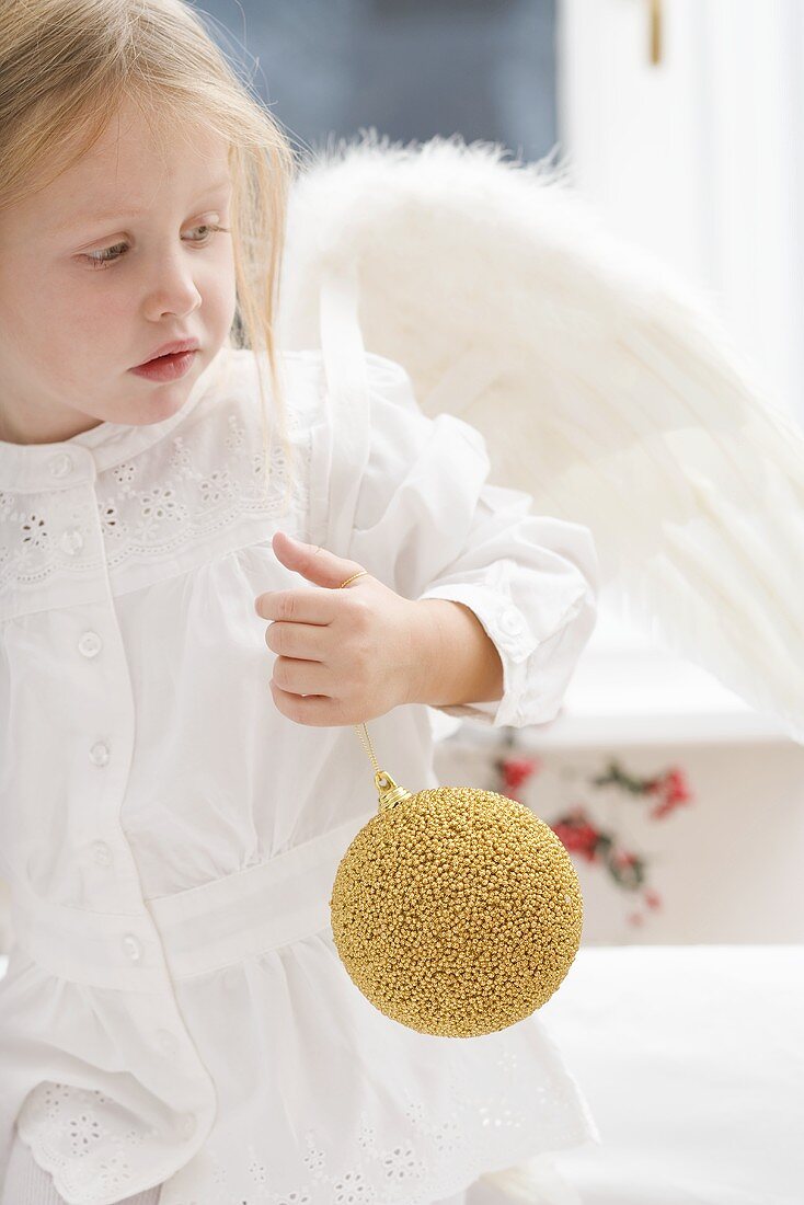 Small girl with angel's wings holding Christmas bauble