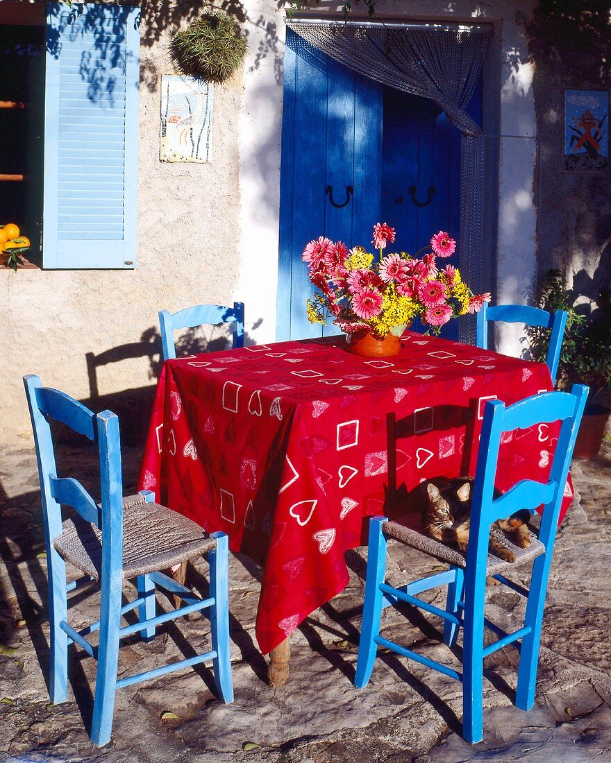 Tisch und blaue Stühle auf einer Terrasse im Süden