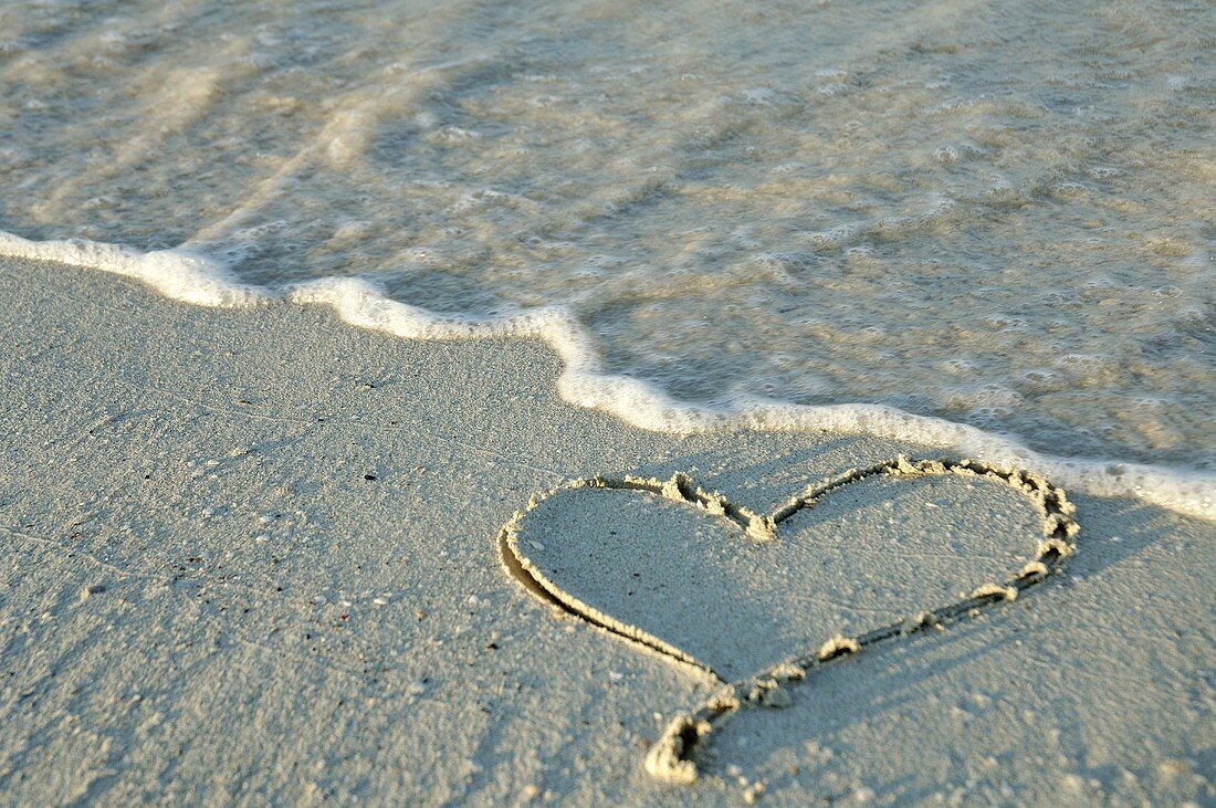 Heart drawn in the sand by the sea