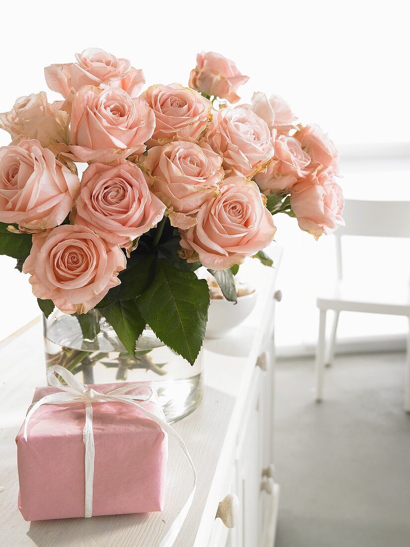 Vase of pink roses and wrapped gift for Mother's Day