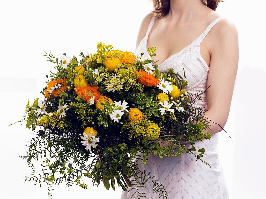 Woman holding bouquet of marigolds and ranunculus