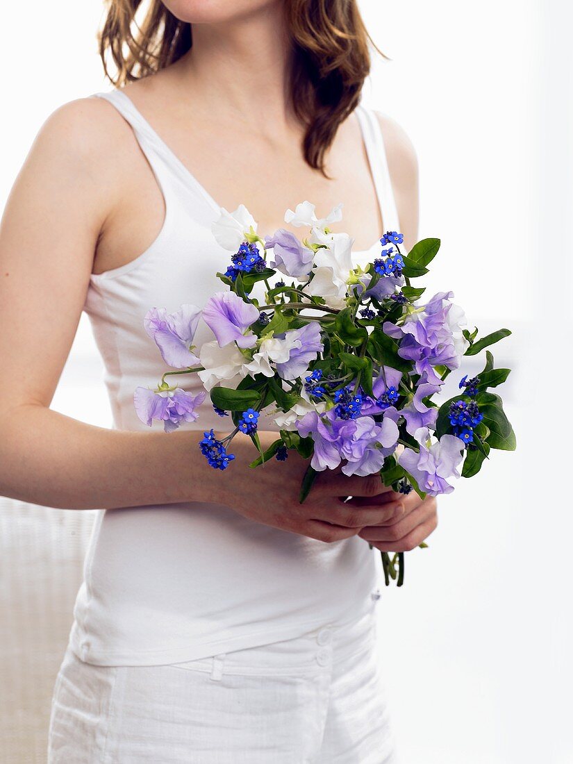 Woman holding bouquet of sweet peas and forget-me-nots