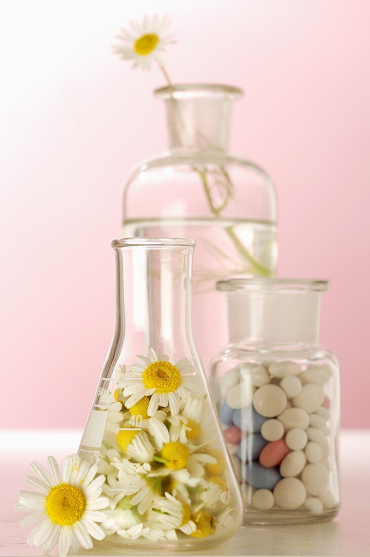 Kamillenblüten und Tabletten in Apothekenfläschchen