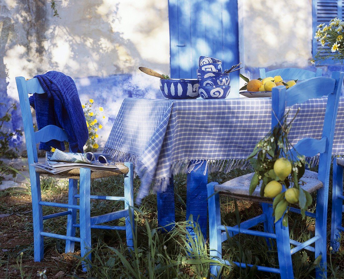 Tisch mit blau-weisser Tischdecke, Geschirr und Zitronen