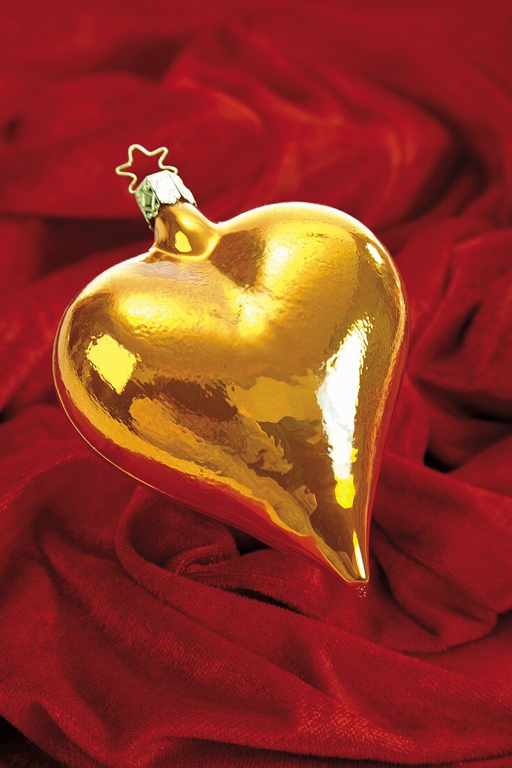 Heart-shaped Christmas bauble on red cloth