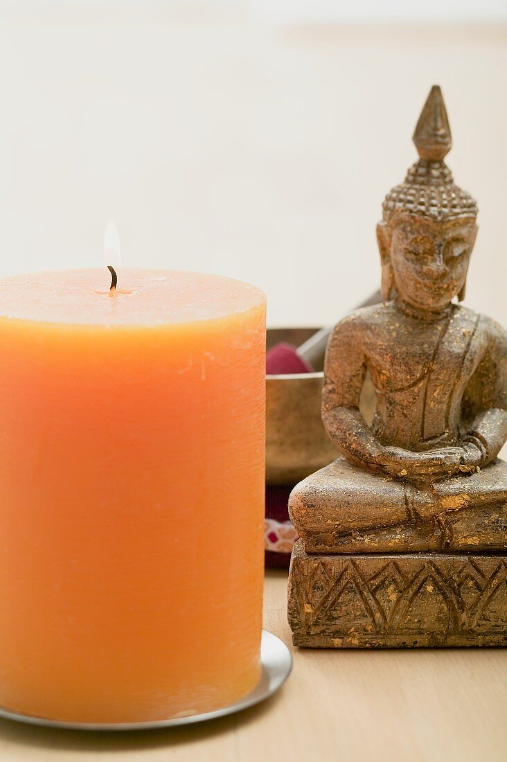 Eine brennende Kerze mit einer religiösen, asiatischen Figur