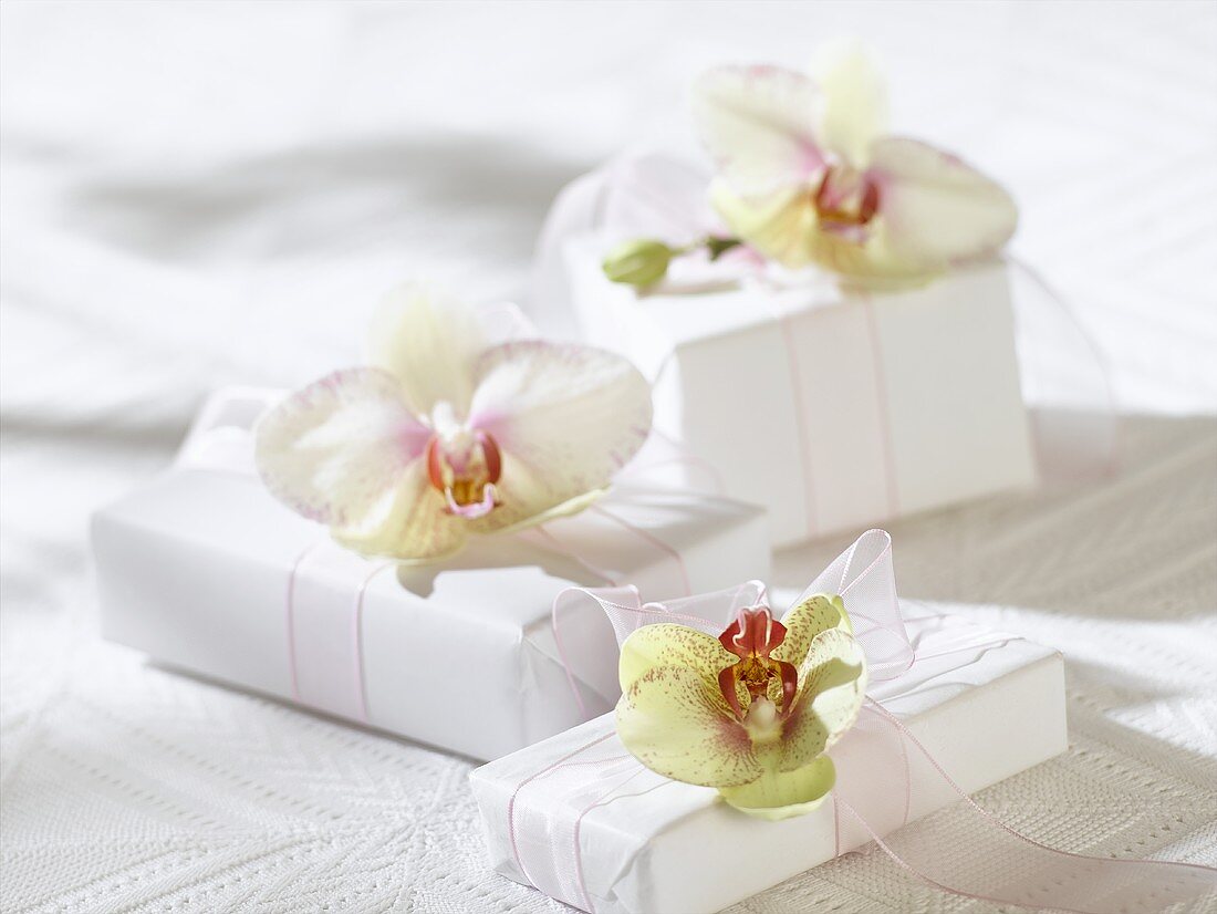 Gifts in white wrapping paper with orchids