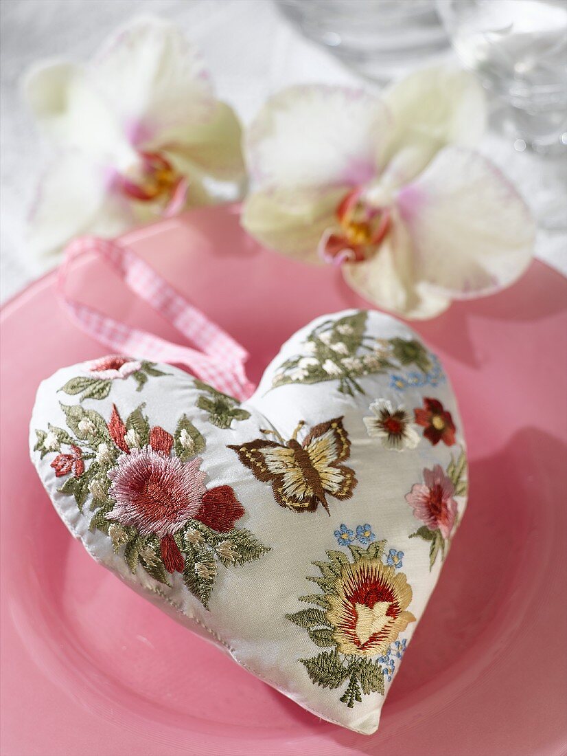 Padded heart in patterned fabric with hanging loop on plate