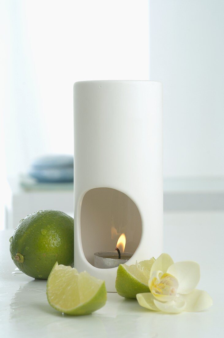 Duftlampe mit Limetten und Orchideenblüte