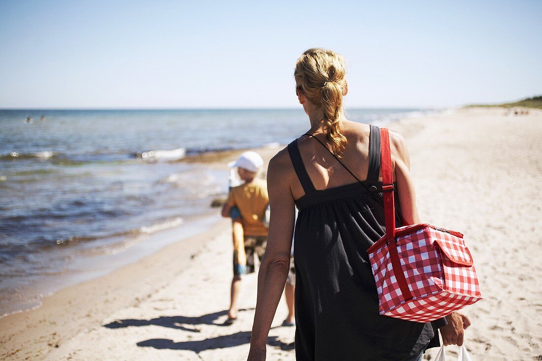 Frau läuft mit Kind am Strand