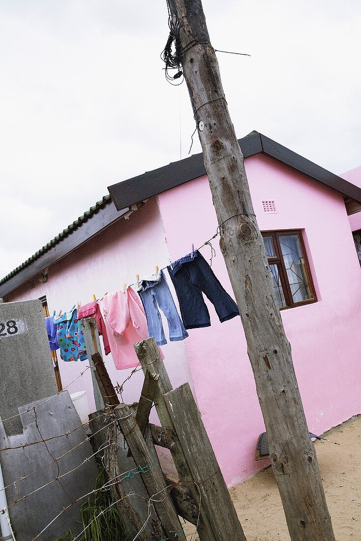 Wäsche hängt auf der Wäscheleine vor einem rosa Haus