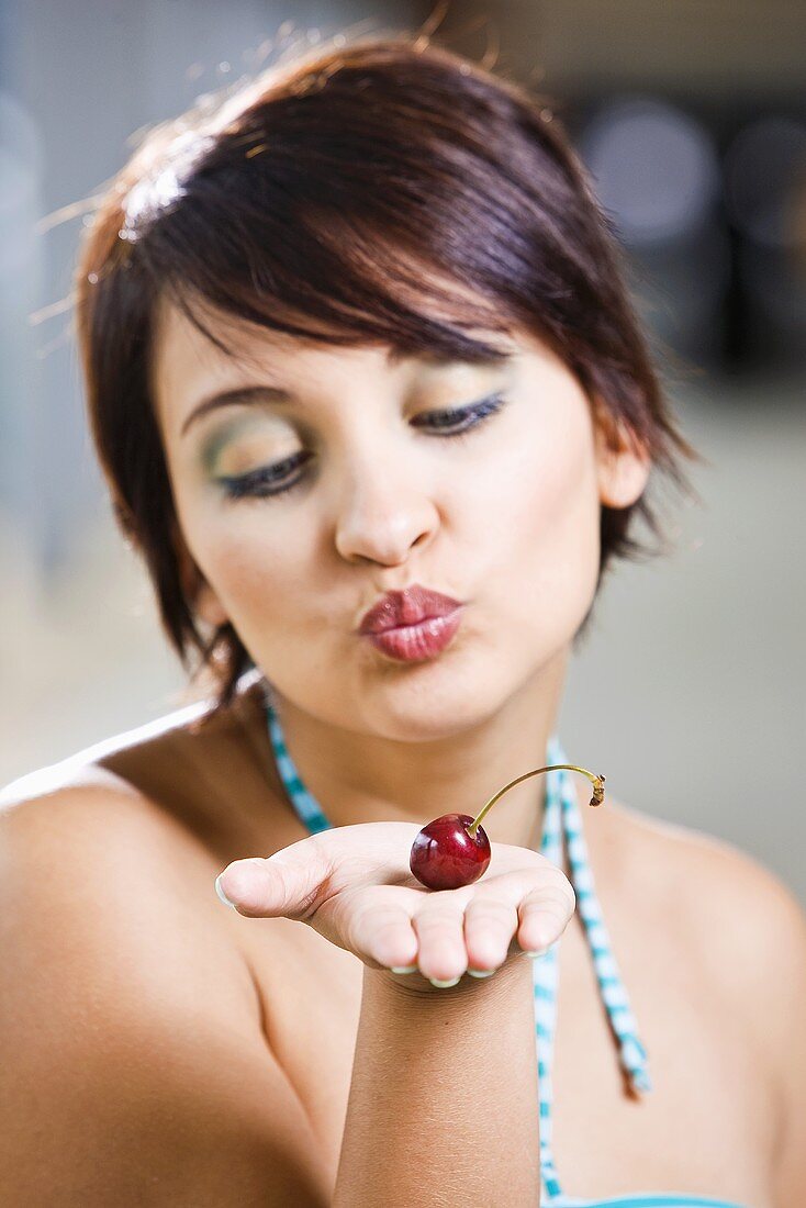 Young woman with a cherry on her hand