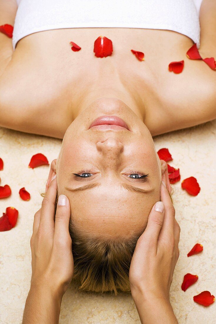 Frau, bestreut mit Blütenblättern, bei Massage