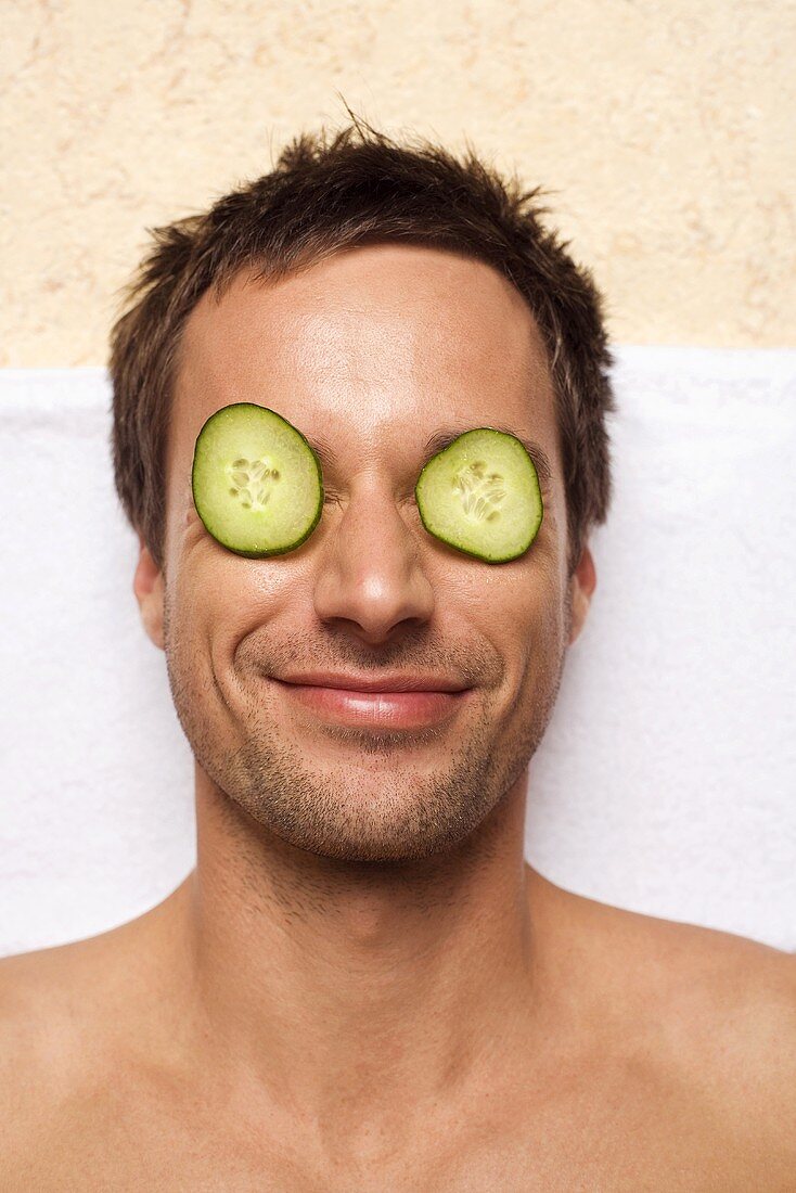 Germany, young man with cucumber slices on eyes