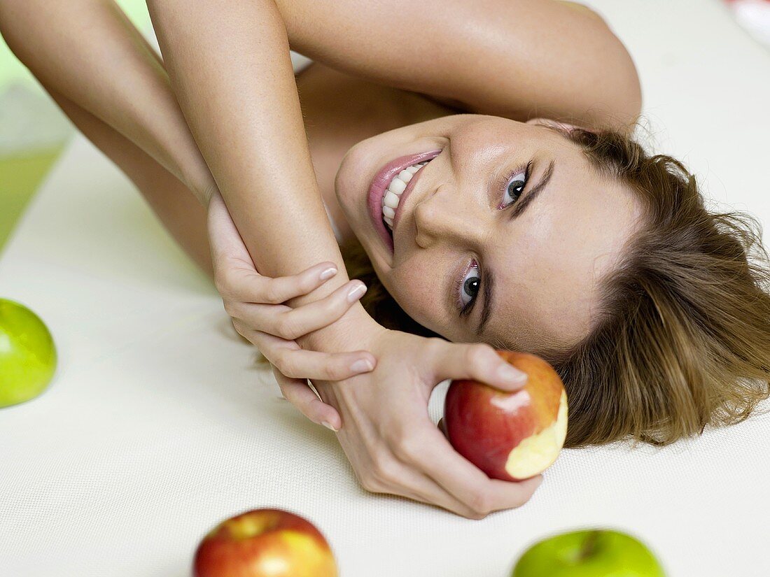 Junge Frau liegt mit Äpfeln auf dem Bett