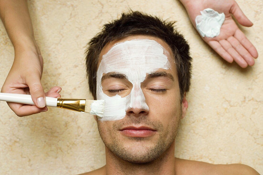 Mann bei Kosmetikbehandlung (Gesichtsmaske wird aufgetragen)