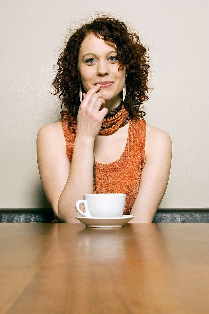 Young woman sitting at table with coffee cup