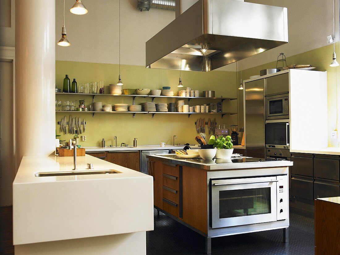 Moderne Küche mit großen, glänzenden Edelstahl- und einfachen Holzfronten, einem Küchenblock und einem langen Geschirrregal