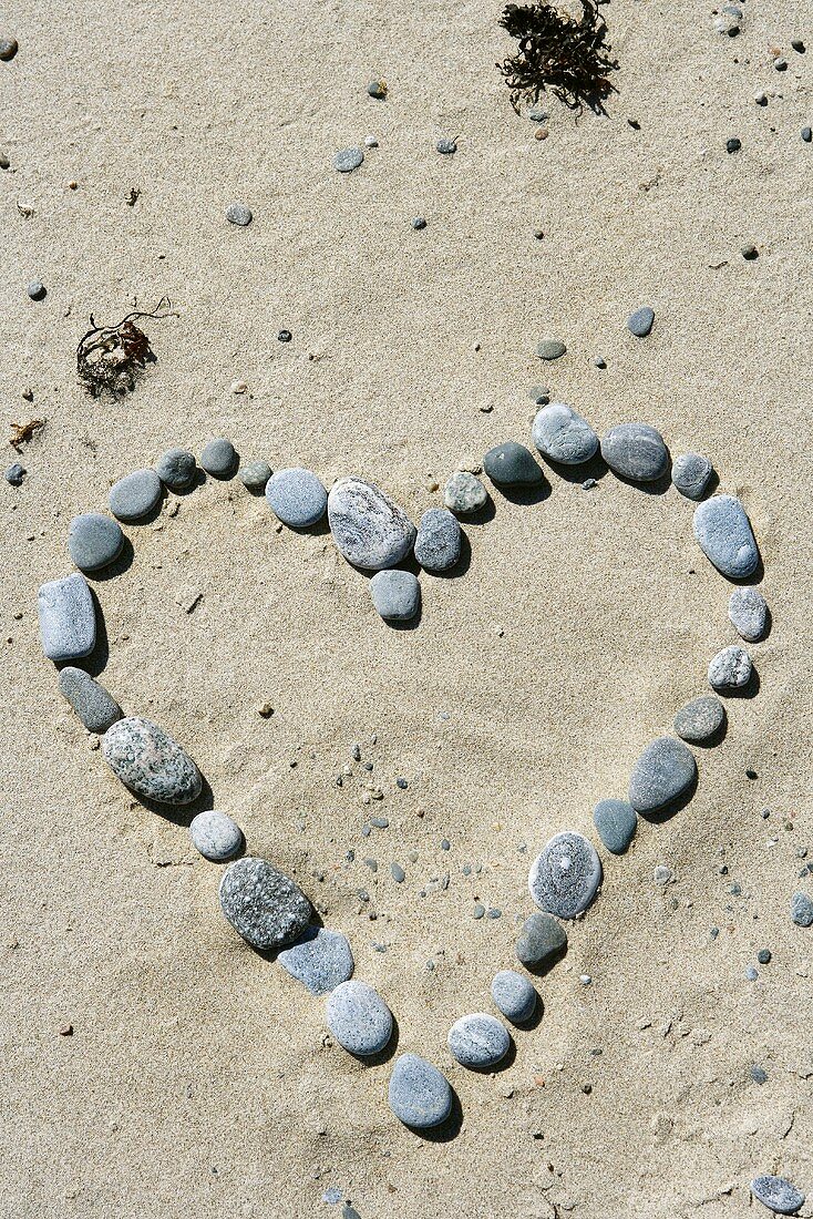 Herzförmig gelegte Steine im Sand